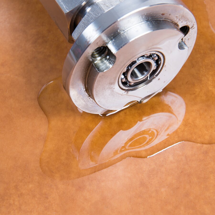 Schützt Metallteile vor Korrosion und Verschmutzung Metallteil auf Ölpapier mit Wasserpfütze